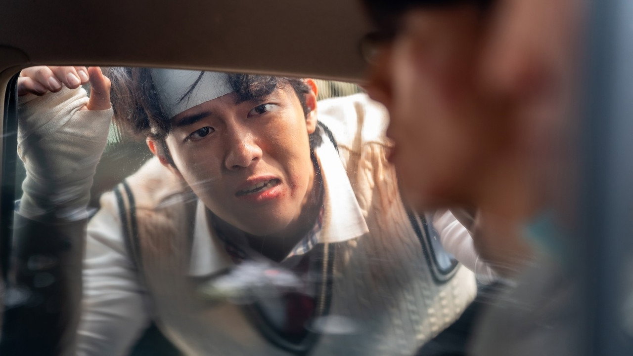 차의 거울에 붕대를 감은 젊은 남성의 얼굴이 비친다