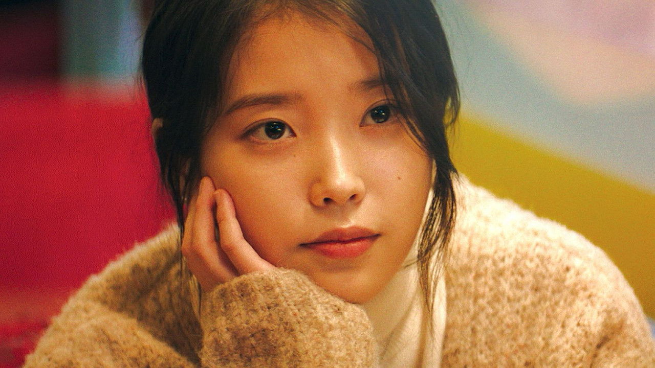 두꺼운 스웨터를 입은 여성이 한 손으로 뺨을 받치고 앞을 바라본다